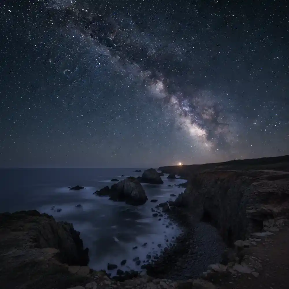 A brilliant starry night sky over a rugged coastline